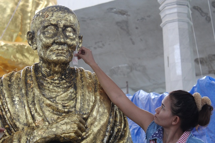 Place gold leaf on buddha statue